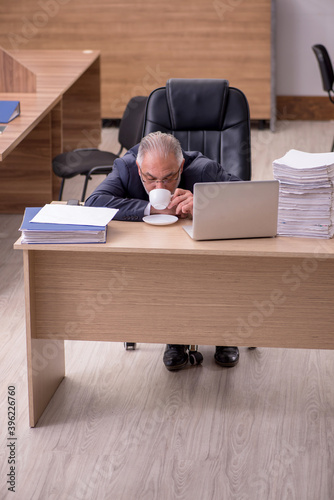 Old male employee drinking coffee during break