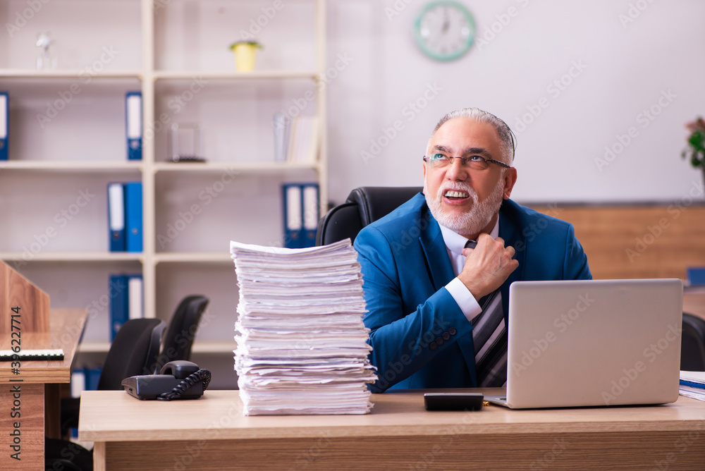 Old male employee unhappy with excessive work in the office Old male employee unhappy with excessive work in the office