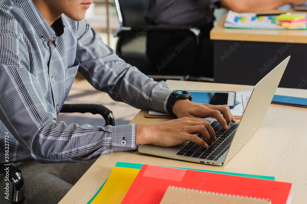 Asian young businessman sitting on desk office he looking at computer monitor during the working day, the confident young handsome man using laptop at workplace