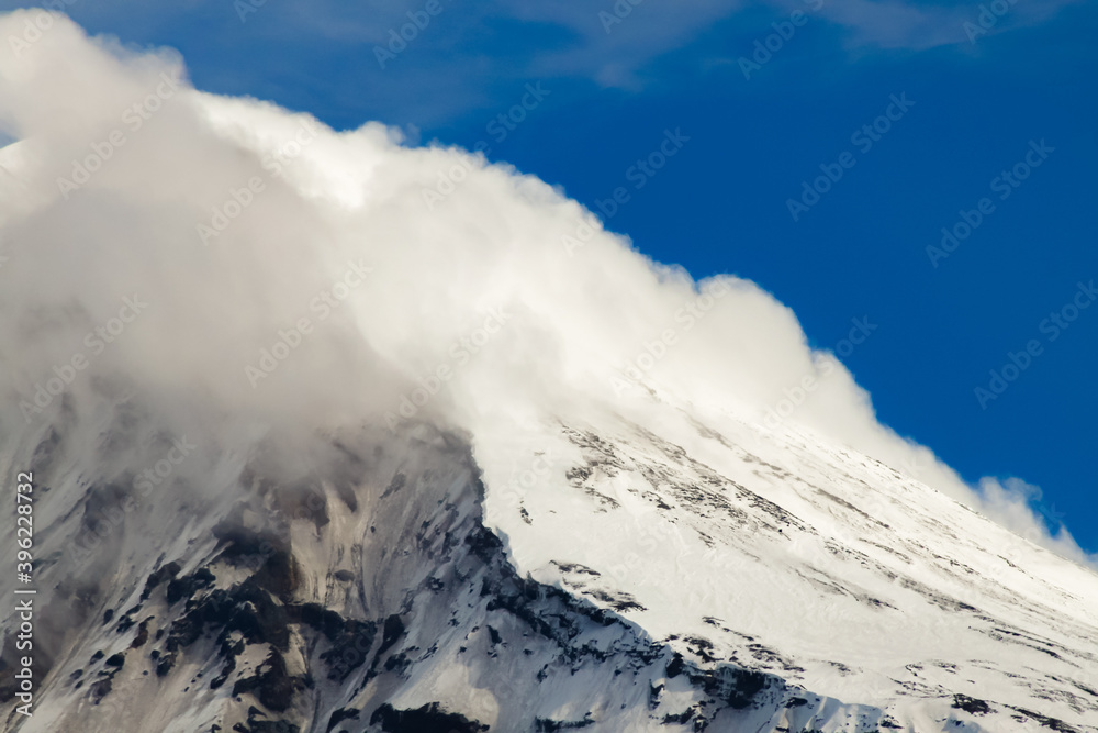 Top of the Lanin Volcano from Lake Tromen in Neuquen, Argentina. This volcano is covered by eternal snow and with some clouds that surround the caldera of the volcano. Top of the Lanin Volcano from Lake Tromen in Neuquen, Argentina. This volcano is covered by eternal snow and with some clouds that surround the caldera of the volcano.