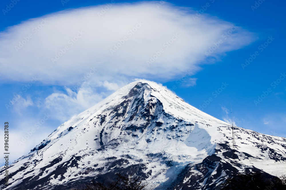 Top of the Lanin Volcano from Lake Tromen in Neuquen, Argentina. This volcano is covered by eternal snow and with some clouds that surround the caldera of the volcano.