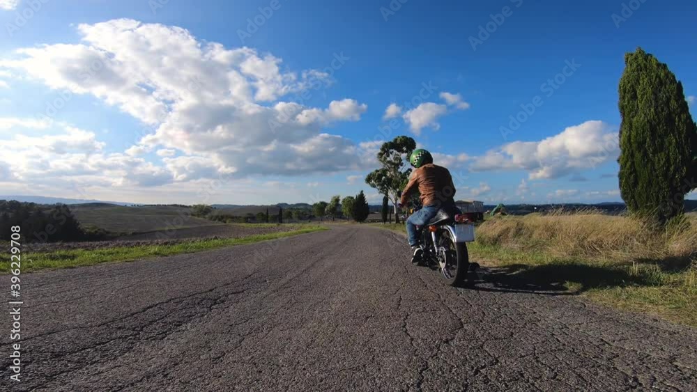 Camera car shot. Man starting and riding red motorcycle in beautiful landscape in Tuscany, Italy. Volterra. Camera car shot. Man starting and riding red motorcycle in beautiful landscape in Tuscany, Italy. Volterra.
