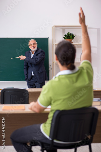 Aged teacher and young male student in the classroom