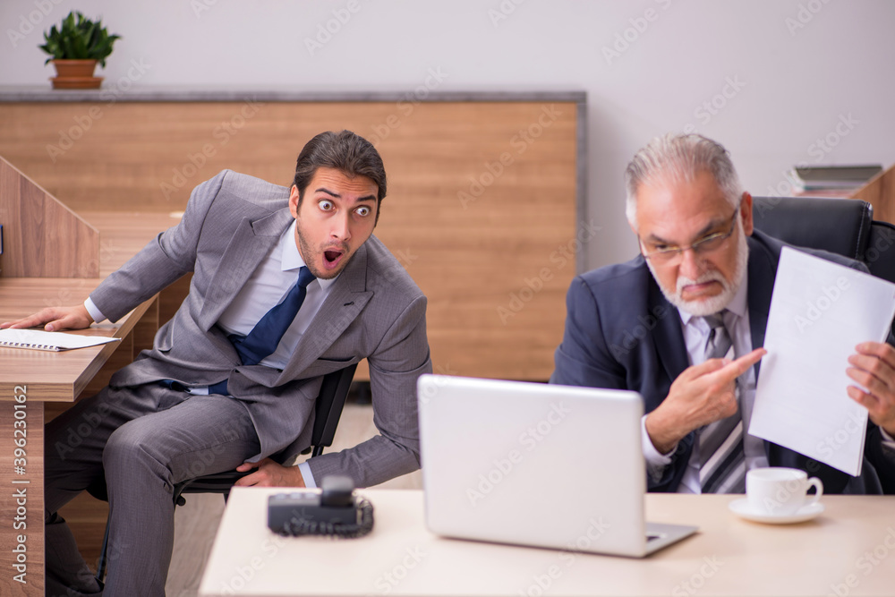 Old boss and young male assistant in the office Old boss and young male assistant in the office