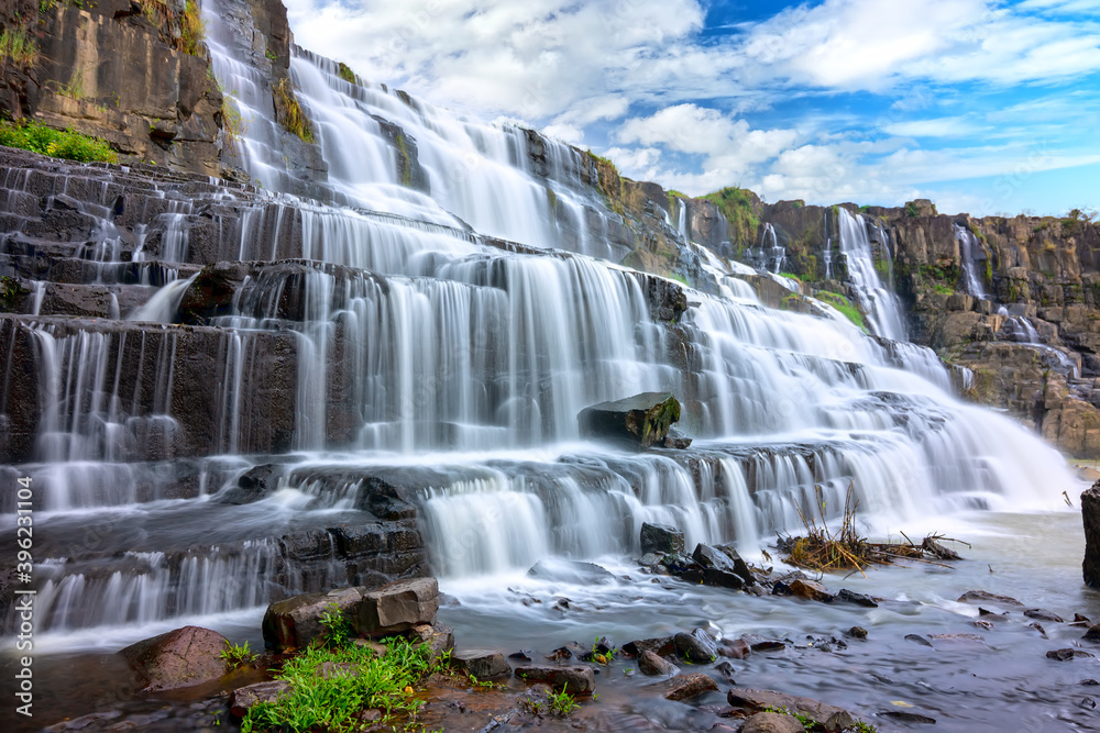 Naklejka premium Waterfall early winter afternoon with water flowing over rocks and moving clouds creating spectacular beauty for the most beautiful water line highlands