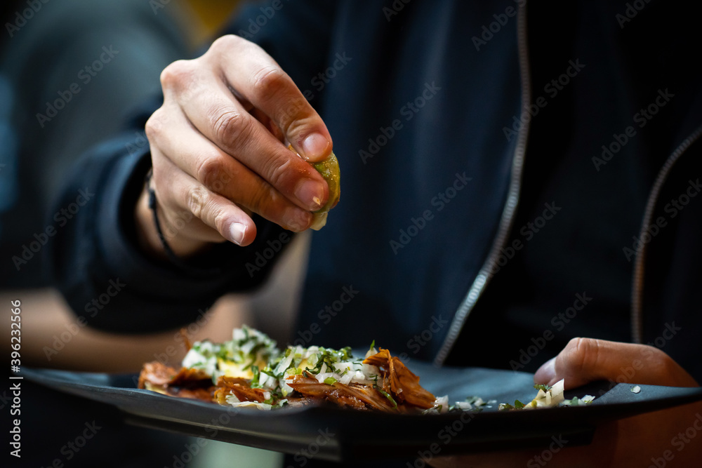 Men squeezing lime into shepherd's taco indoors, close-up Men squeezing lime into shepherd's taco indoors, close-up