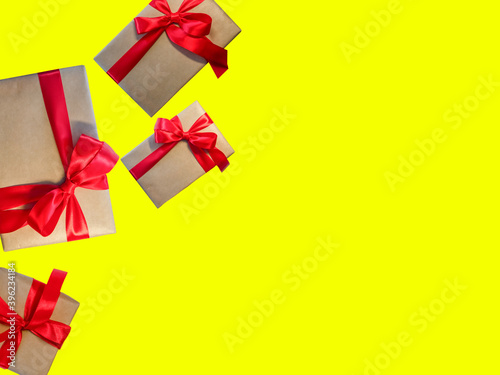 Fototapeta Naklejka Na Ścianę i Meble -  Gift boxes with red ribbon, copy space on a yellow background. Sales concepts, discount price, Christmas gifts and shopping, Greeting card for Christmas, Valentine's Day or New Year
