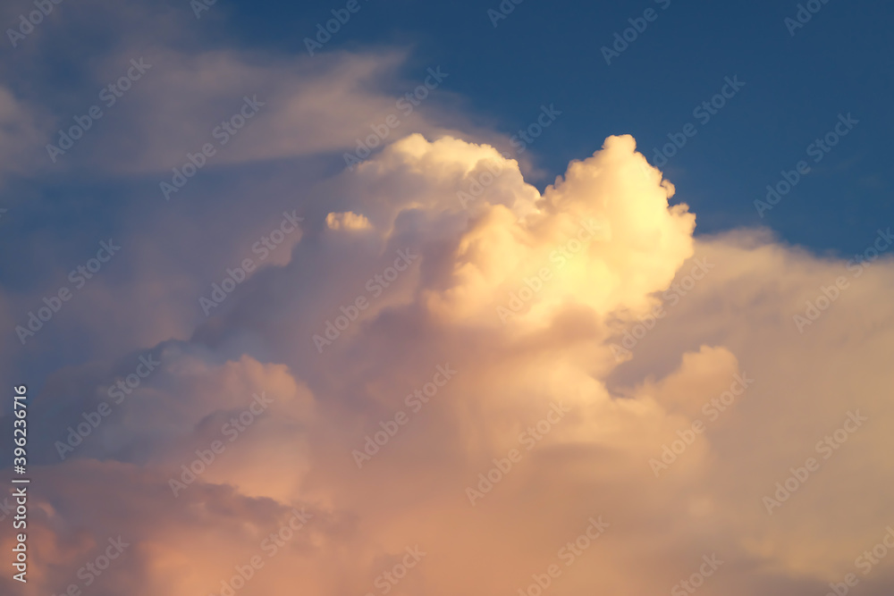 Large white cumulus clouds with blue sky on sunset sky. Fluffy clouds and dramatic twilight sunset background.