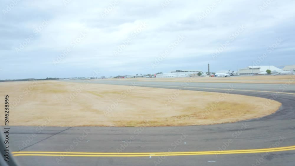 Slow motion shot looking out of plane window with runway and airport in background on dark gloomy day Slow motion shot looking out of plane window with runway and airport in background on dark gloomy day