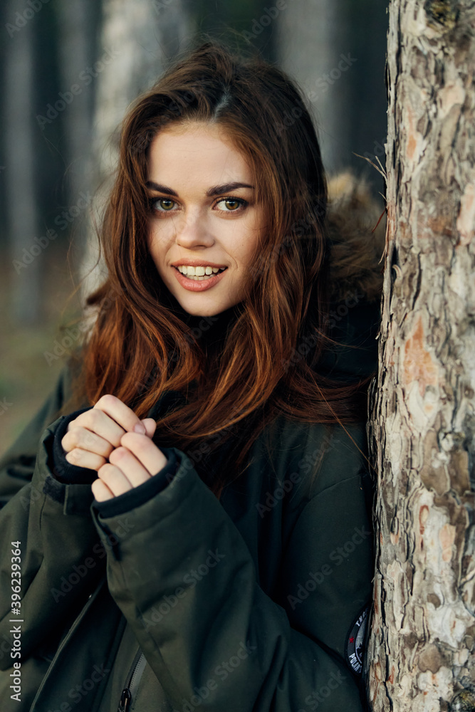 Fototapeta premium woman in a warm jacket near a tree in the forest attractive travel look