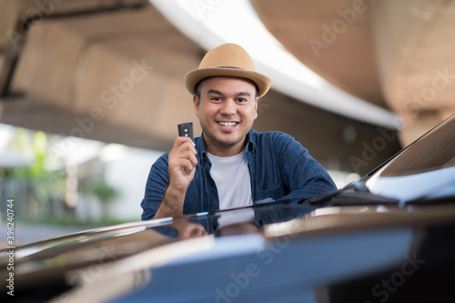 Young handsome asian man getting the new car.He showing car key and very happy. Buy or rent a car concept. © Chanakon