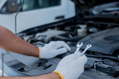 Auto mechanic holding wrench prepair to car service care. Car open the bonnet to checking engine and service.