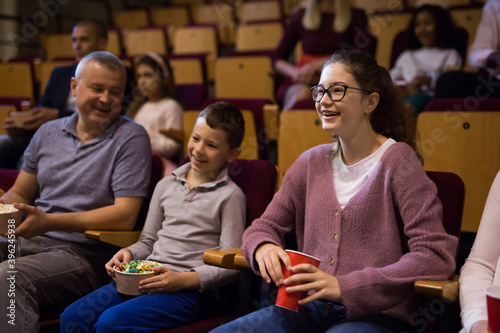 mother, father and their children sitting at comedy in auditorium