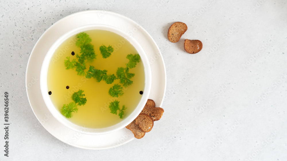 Homemade turkey bone broth in white bowl with parsley leaves, peppercorns and croutons. Health benefits. Collagen is good for joints. Collagen provides the body with amino acids. Top view. Homemade turkey bone broth in white bowl with parsley leaves, peppercorns and croutons. Health benefits. Collagen is good for joints. Collagen provides the body with amino acids. Top view.