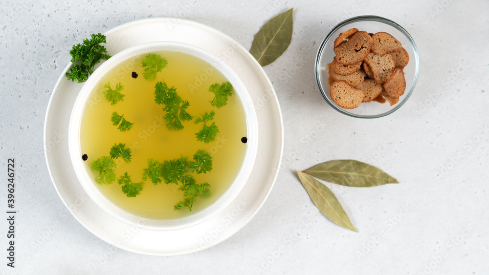 Homemade turkey bone broth in white bowl with bay leaves, parsley, peppercorns and croutons. Health benefits. Collagen is good for joints. Homemade turkey bone broth in white bowl with bay leaves, parsley, peppercorns and croutons. Health benefits. Collagen is good for joints.