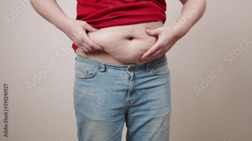 Cellulite on the stomach of an elderly woman. A fat woman eyeing a belly in the mirror. concept of diet and proper nutrition, close-up