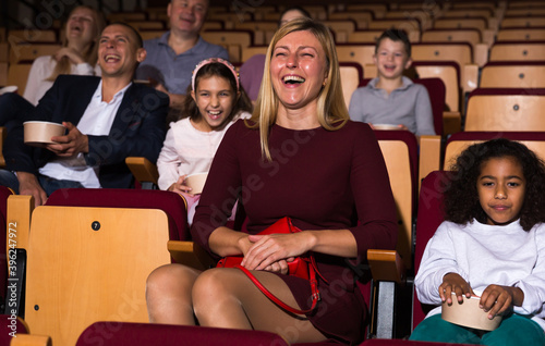 Family with child eating popcorn and watching a movie in the cinema