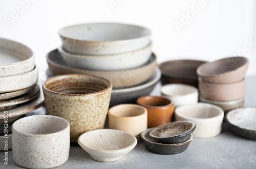 handmade ceramics, empty craft ceramic plates and bowls on light background 