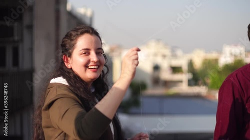 Young indian girl woman flying a kite by pulling on the thread on the festival of makar sankranti uttarayana independence day on the roof of an urban colony shot with shallow depth of field photo