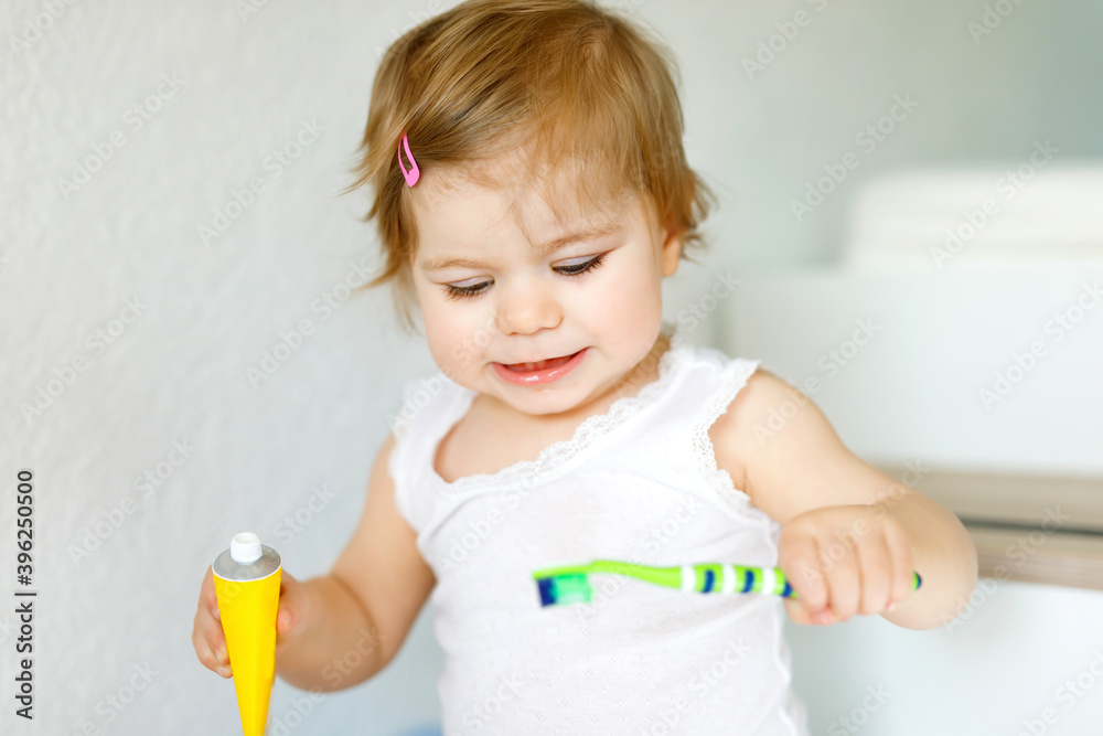 Little baby girl holding toothbrush and brushing first teeth. Toddler learning to clean milk tooth. Little baby girl holding toothbrush and brushing first teeth. Toddler learning to clean milk tooth.