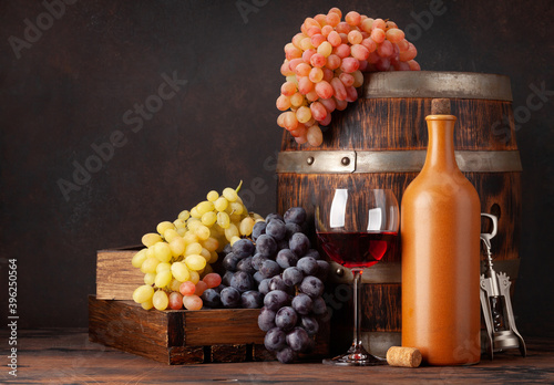 Wine bottles, grapes, glass of red wine and old barrel