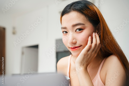 Portrait of young asian woman working on laptop at home.
