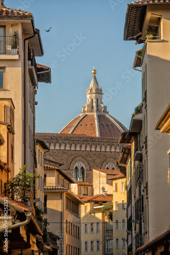 View of the dome of Il Duomo church seen down a side street between buildings in the centre of Florence