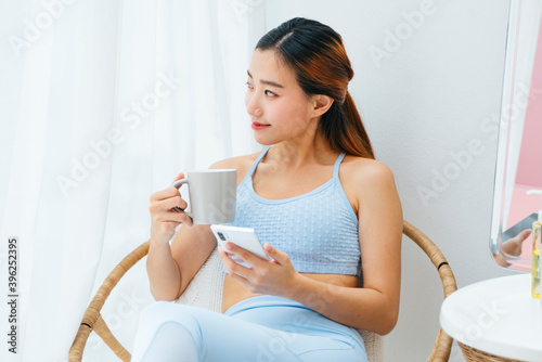 Beautiful sporty woman wearing sportbra holding coffee cup and smartphone. photo