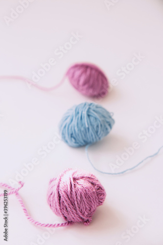 Three skeins of multi-colored woolen yarn with the falling rays of the sun on a light background with copy space