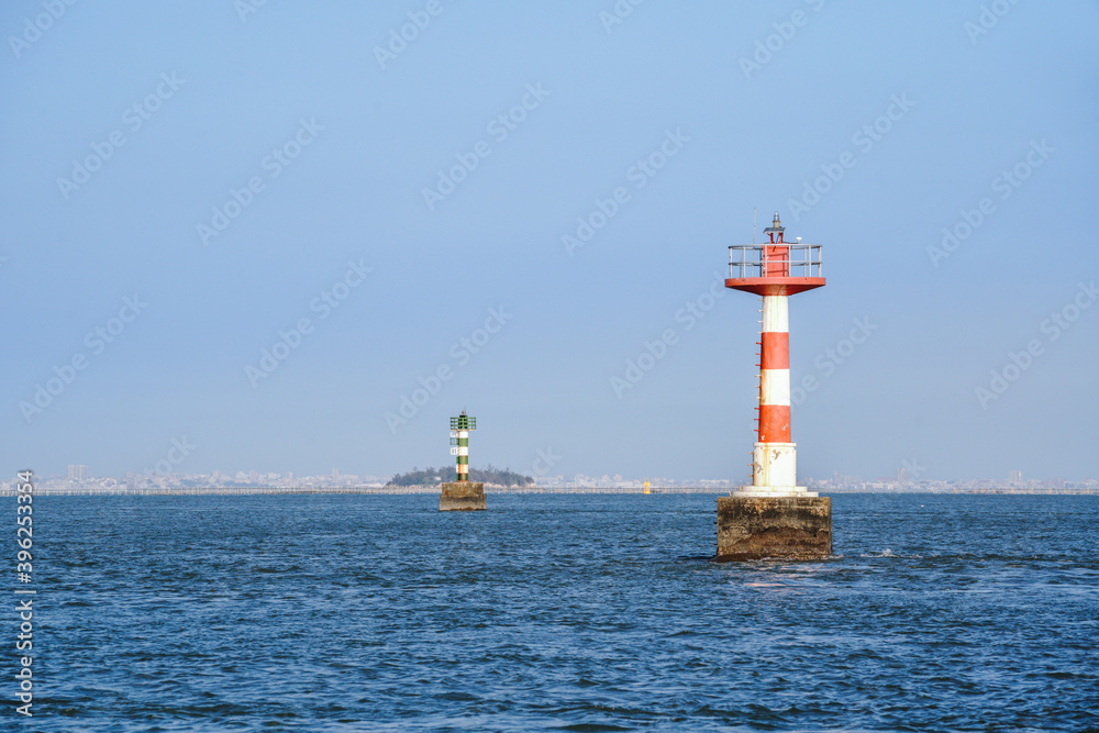 Lighthouse on the sea against blue sky and blue ocean surface