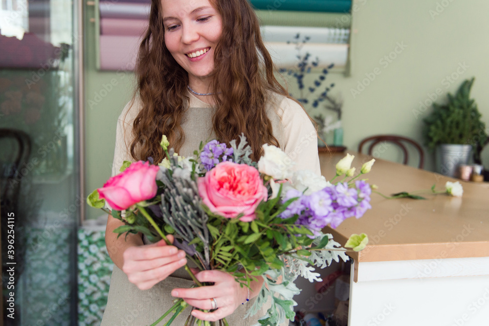 Young woman florist makes a bouquet at workplace, small business concept, lifestyle Young woman florist makes a bouquet at workplace, small business concept, lifestyle