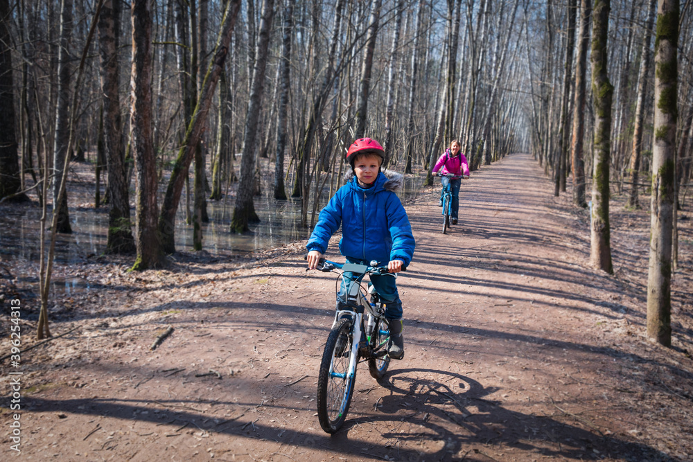 Naklejka premium family on bike ride in spring, mother and son exercise in nature