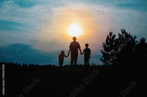 father with son and daughter walk at sunset