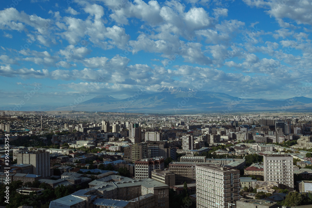 Cityscape of Yerevan city with buildings rooftops under blue sky with clouds in Armenia 