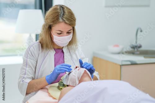 Woman beautician doctor at work in spa center. Portrait of a young female professional cosmetologist. Healthcare occupation, medical career. Young woman doctor preparing patient to beauty procedures.