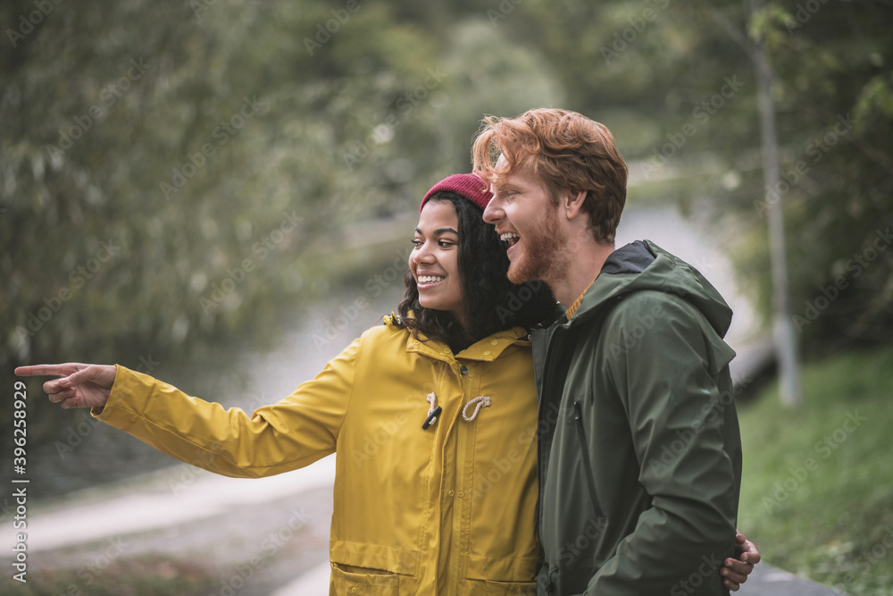 Partners pointing at a beautiful place in the park while walking Partners pointing at a beautiful place in the park while walking
