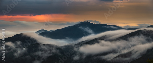 Skofja Loka, Slovenia - Panoramic view of the mountains of Kranj region taken from Jamnik with summer morning fog and golden sky at sunrise