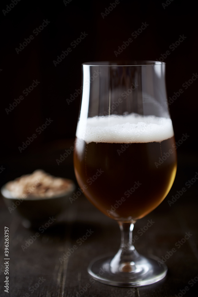 Glass of beer on dark wooden background.