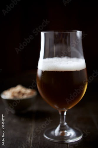 Glass of beer on dark wooden background.