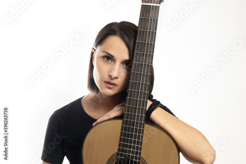 Portrait of young beautiful brunette with classical guitar on white background.