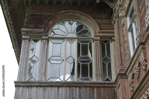 Ornamental window with carved frame of ancient rural wooden house (