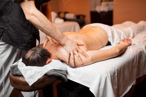 Man receiving a deep massage on his back from professional therapist at luxury spa salon