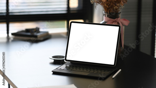 Front view of a computer tablet on modern workspace and blank screen for graphics display montage.