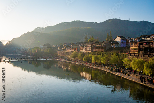 the river, the boat, stone bridge and the old houses at ancient phoenix town in the morning at Hunan, China. © Nhan