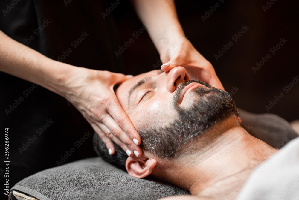 Bearded man receiving a facial massage, relaxing at Spa salon, close-up