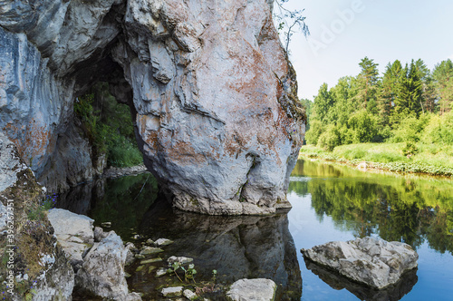 A huge rock in the form of the head of a drinking horse in the Serga River in the Olenyi Streams Nature Park, Russia.