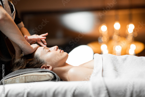 Young woman receiving a facial massage, relaxing at Spa salon