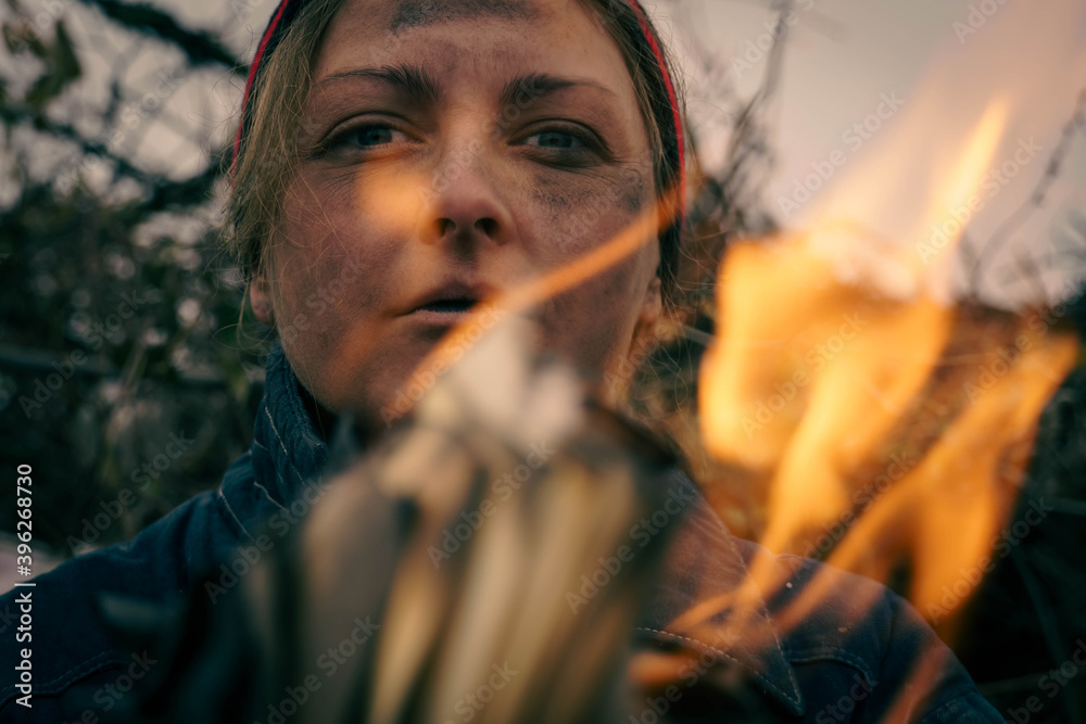 Close-up of a female dirty face through the fire. Homeless by the fire.
