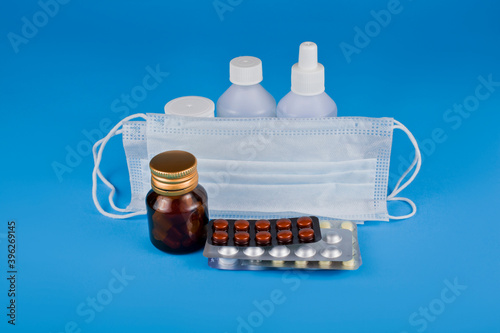 Medicine bottles with pills and mask on a blue background. photo