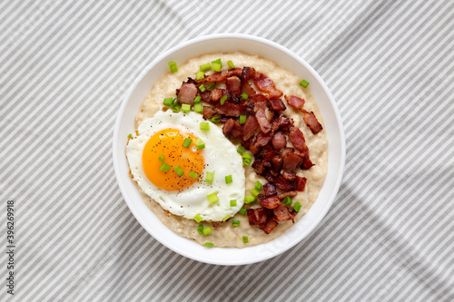 Homemade Cheesy Bacon Savory Oatmeal Bowl on cloth, overhead view. Top view, from above, flat lay.